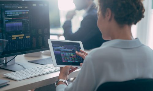 A businesswoman using a tablet while working working with financial market forecasts.