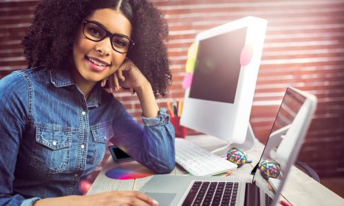 Portrait of casual female designer using laptop at workplace